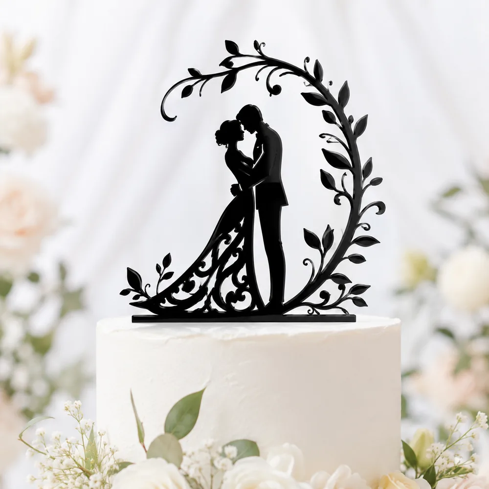 Black acrylic silhouette cake topper of a bride and groom framed by a decorative vine wreath
